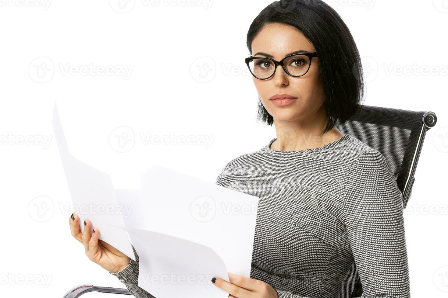 Pensive young business woman in glasses sitting on chair with paper documents. Isolated over white background. Achievement business career concept. photo