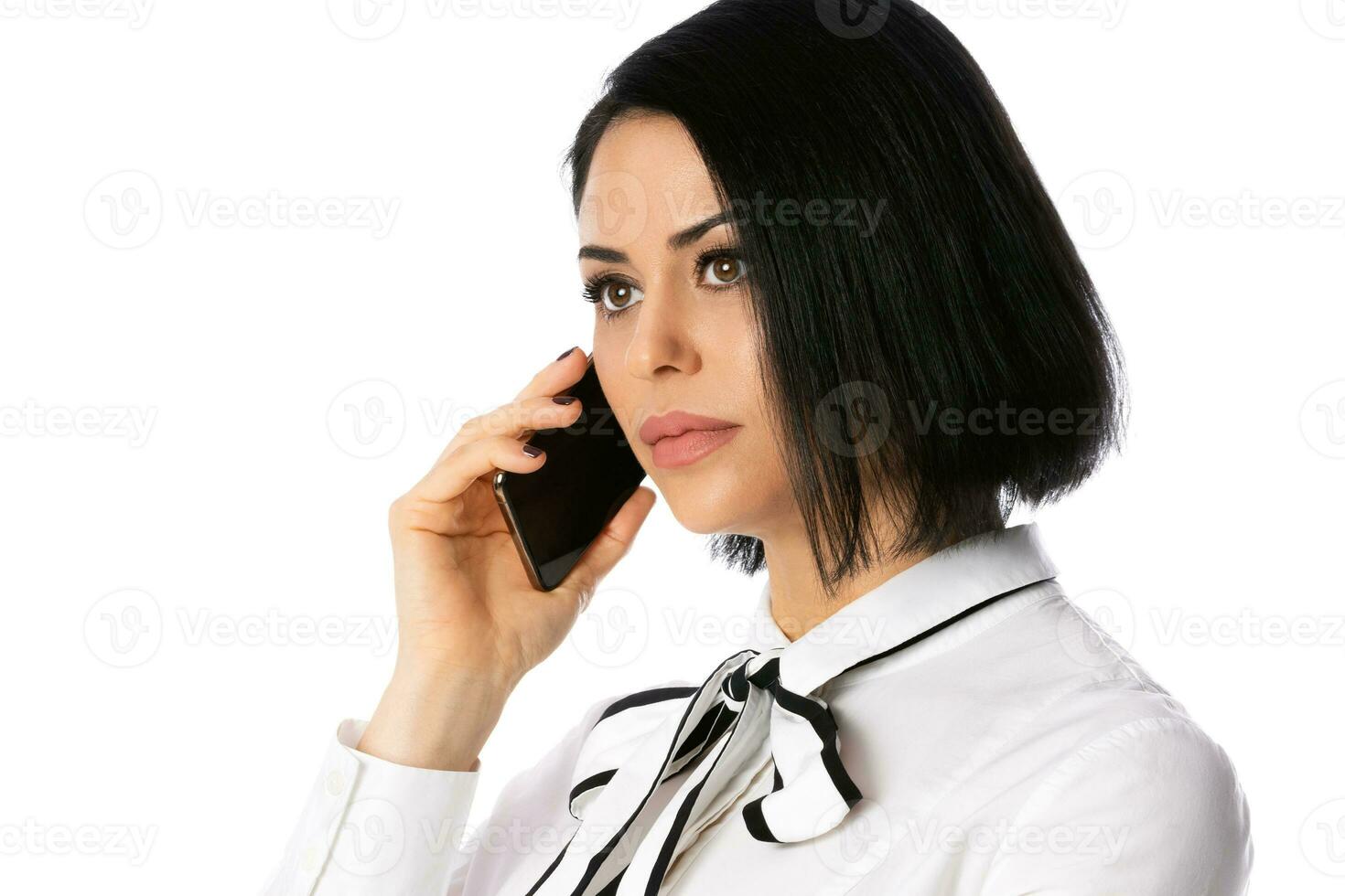 Business talk. Portrait of confident young businesswoman in white shirt talking on the mobile phone, isolated photo