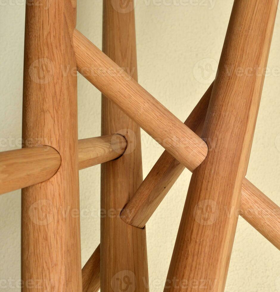 Wooden table legs isolated over gray background, close view photo, crossed star shaped legs, wooden eco furniture elements. Solid wood furniture complicated construction photo