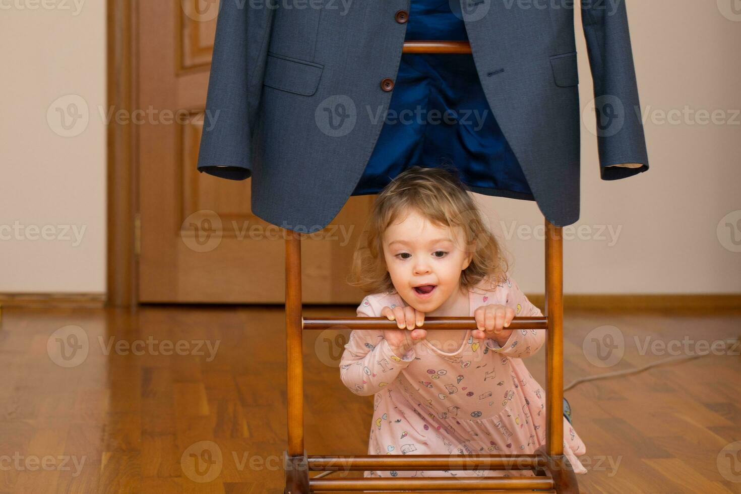 a little girl is hiding behind a suit photo