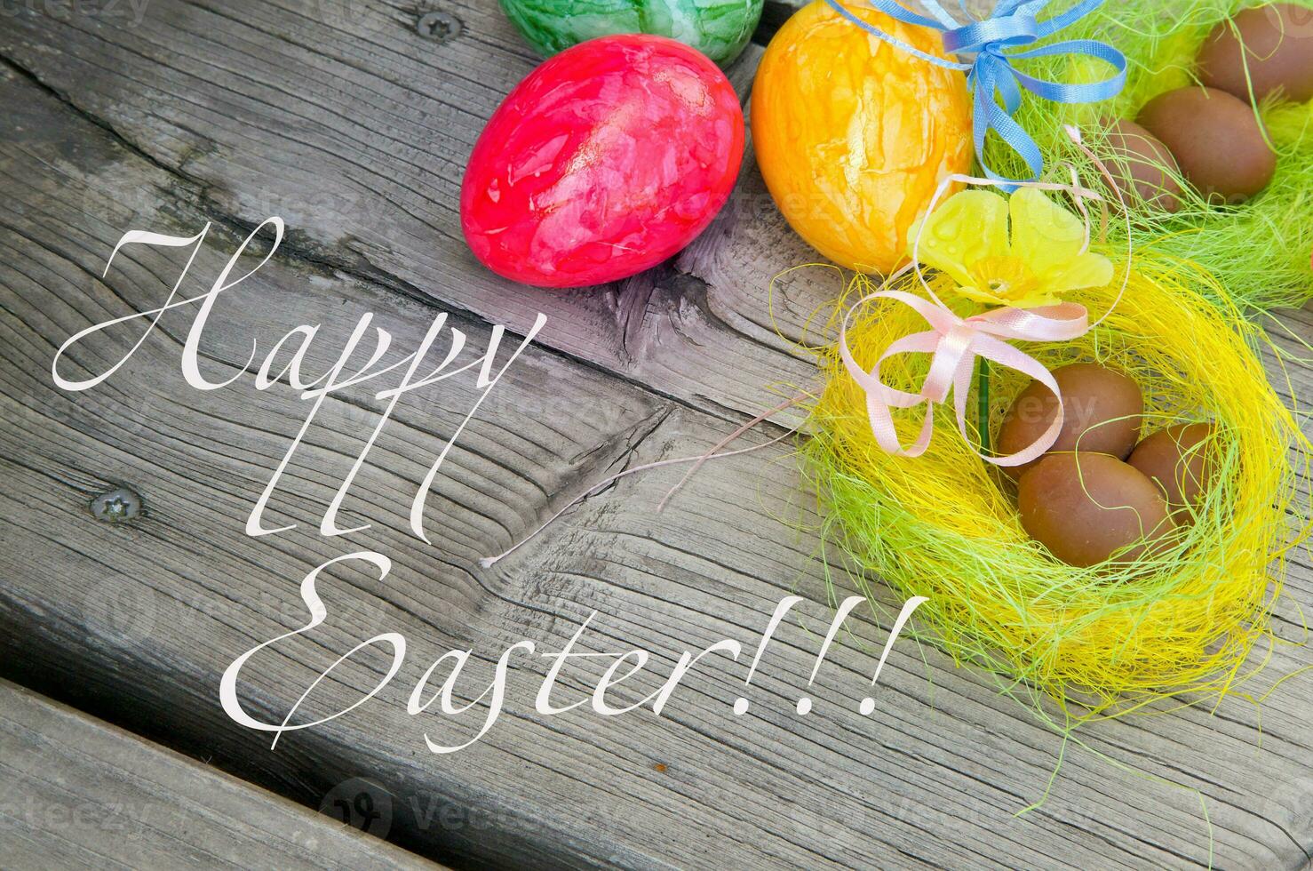 easter eggs and nest on wooden background with happy easter text photo