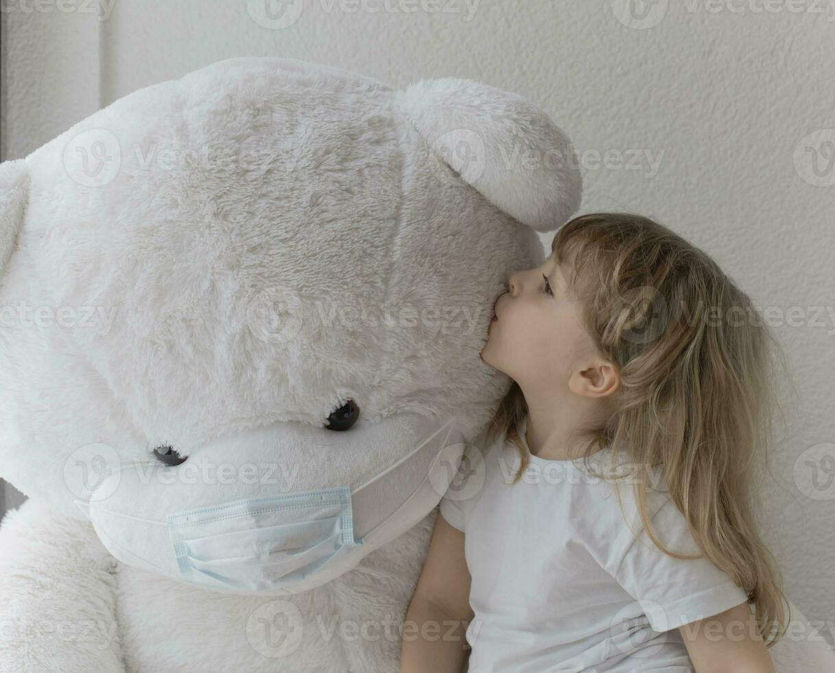 a little girl is kissing a giant teddy bear photo