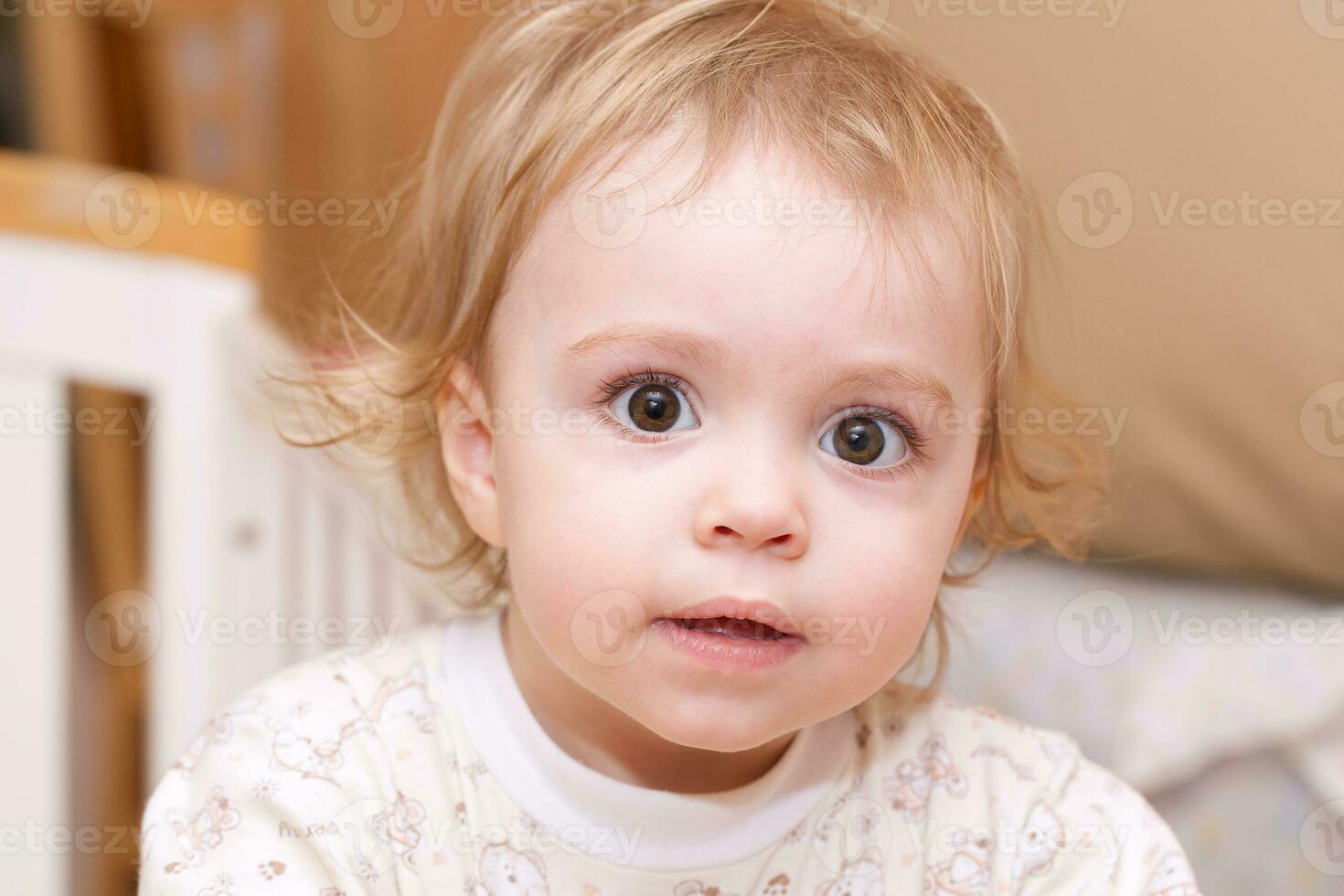 a baby sitting in a crib with a toy photo