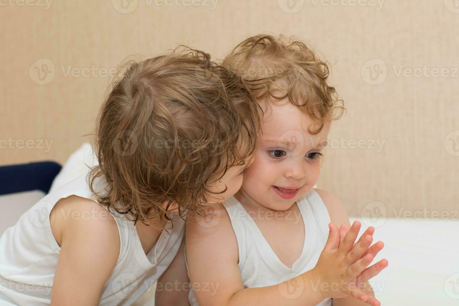 two children are playing on a bed photo