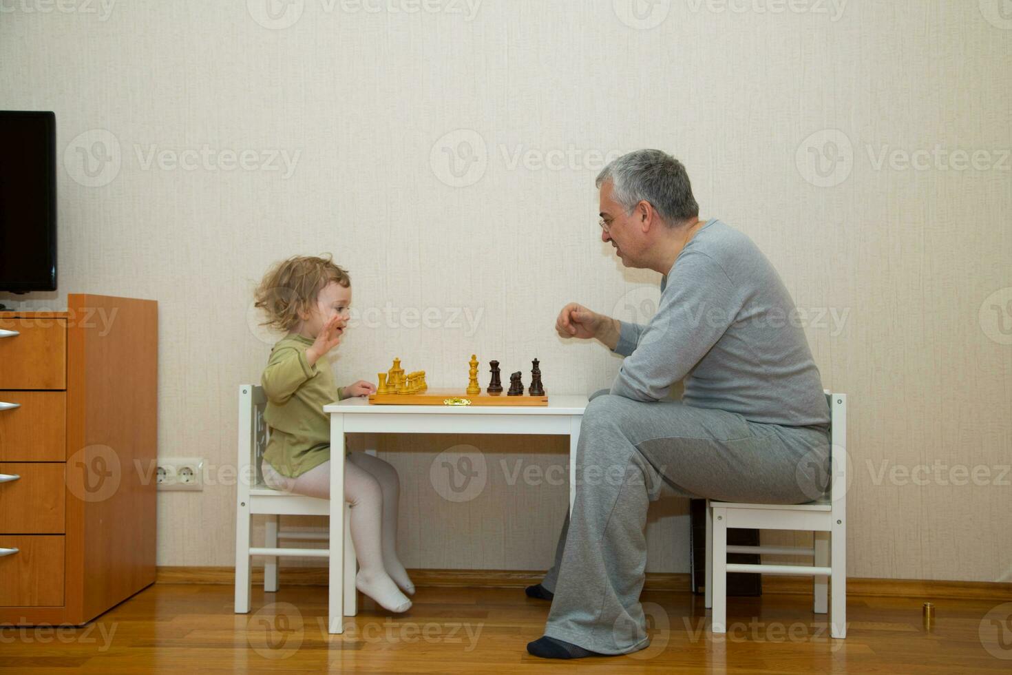 grandfather and granddaughter playing chess in the living room photo