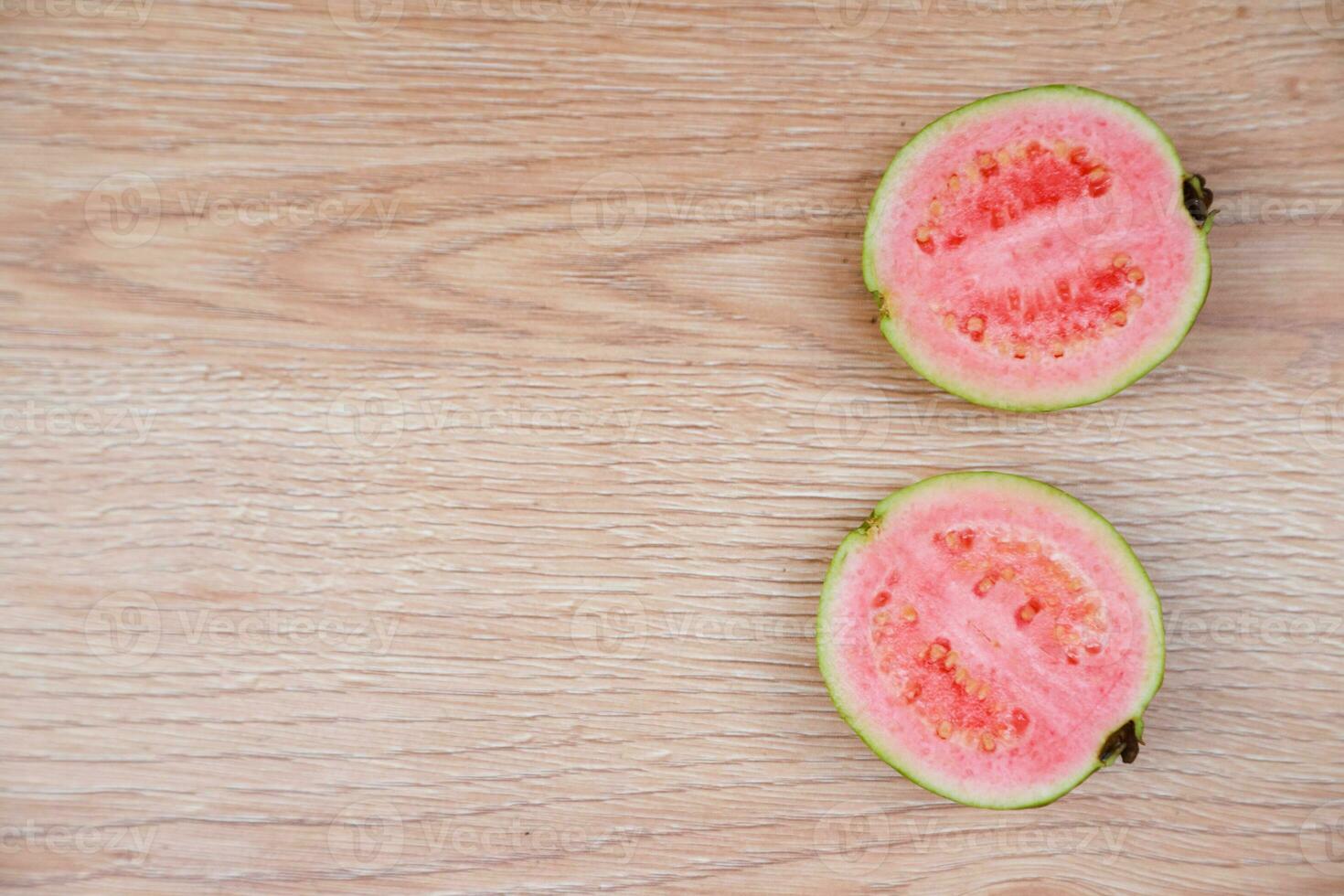Flatlay of half cut fresh guava on the wooden table photo