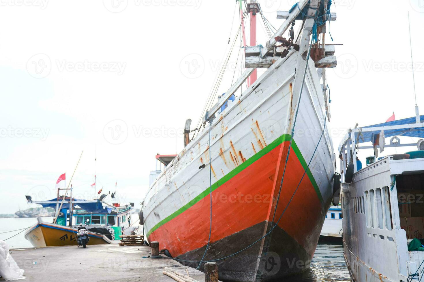 Several wooden boats and cargo ships moored at the traditional port while waiting for loading and unloading photo