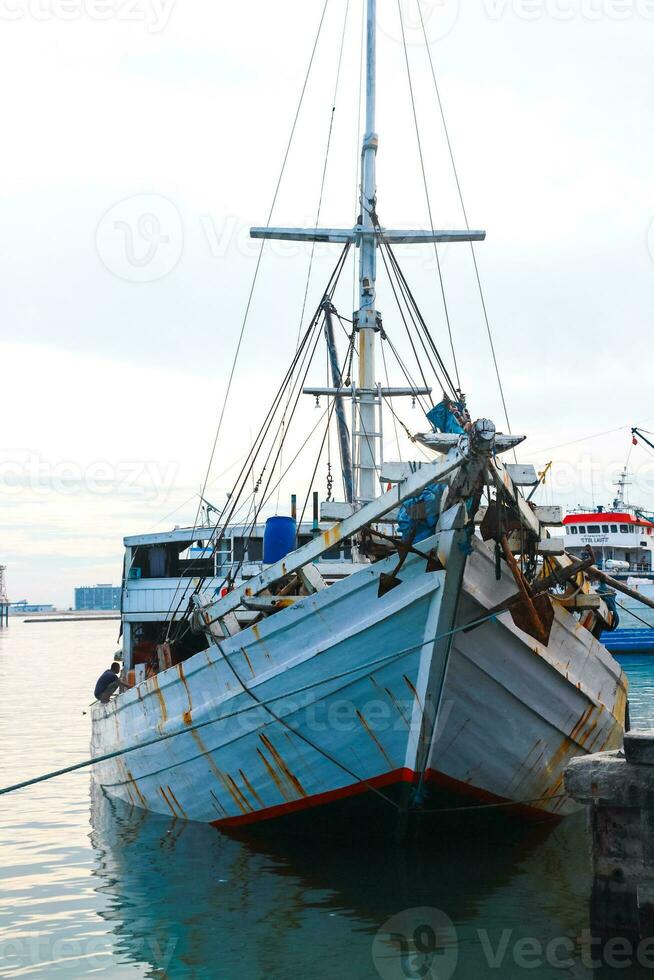 Several wooden boats and cargo ships moored at the traditional port while waiting for loading and unloading photo