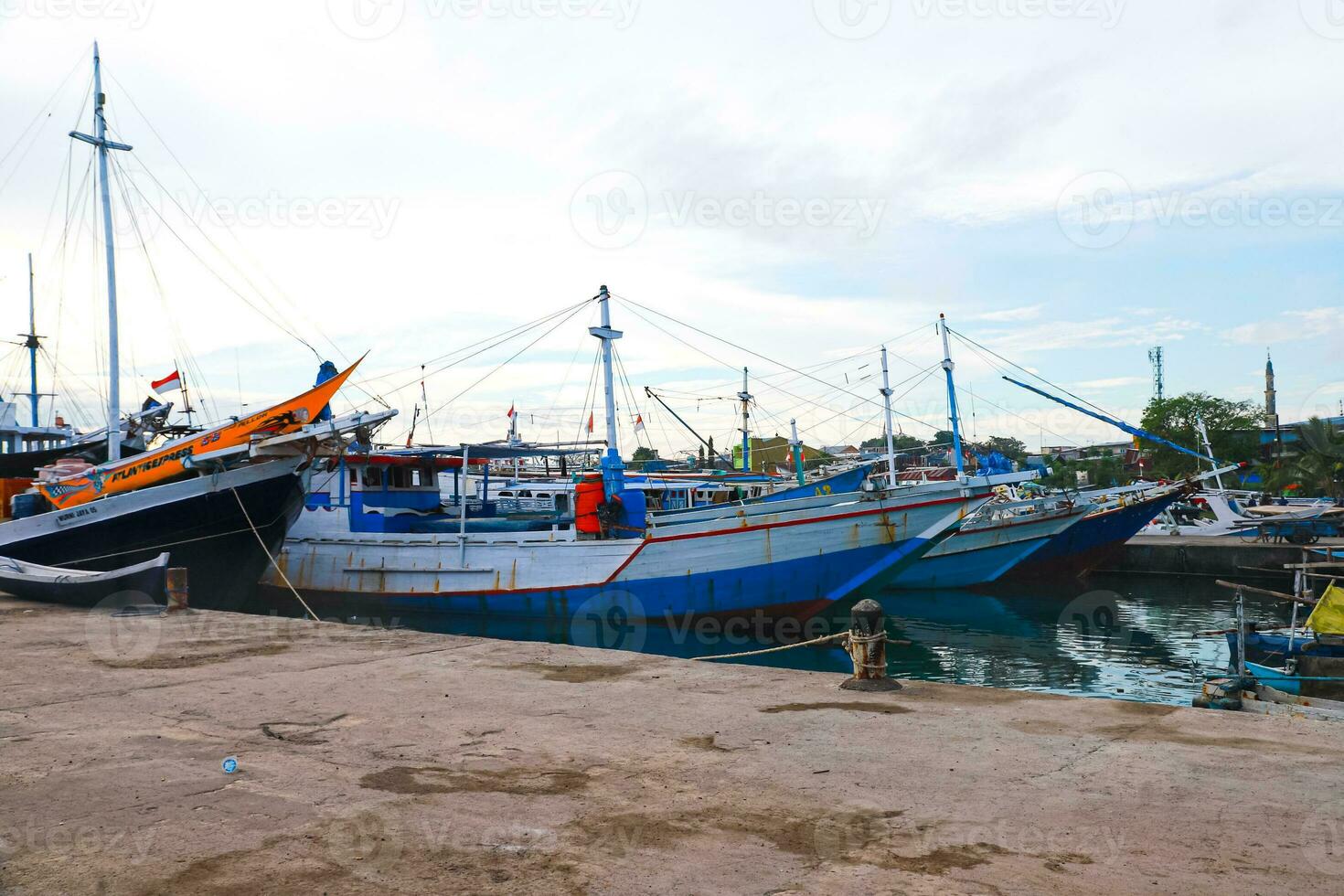 Several wooden boats and cargo ships moored at the traditional port while waiting for loading and unloading photo