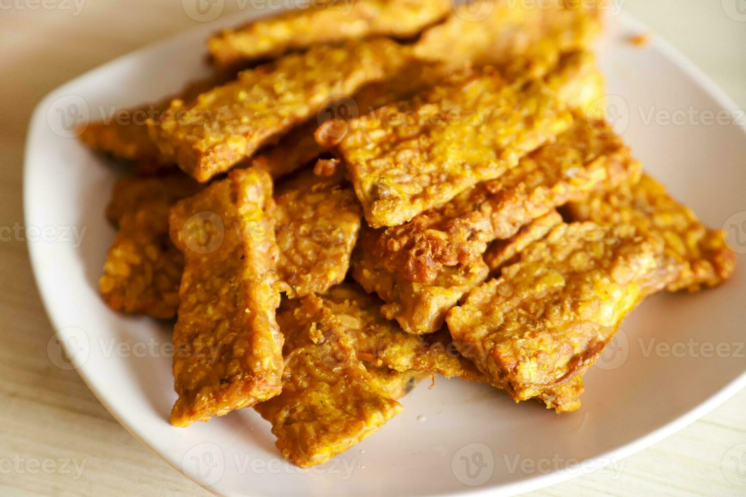 Tempe goreng or fried tempeh is served on a plate along with sambal photo