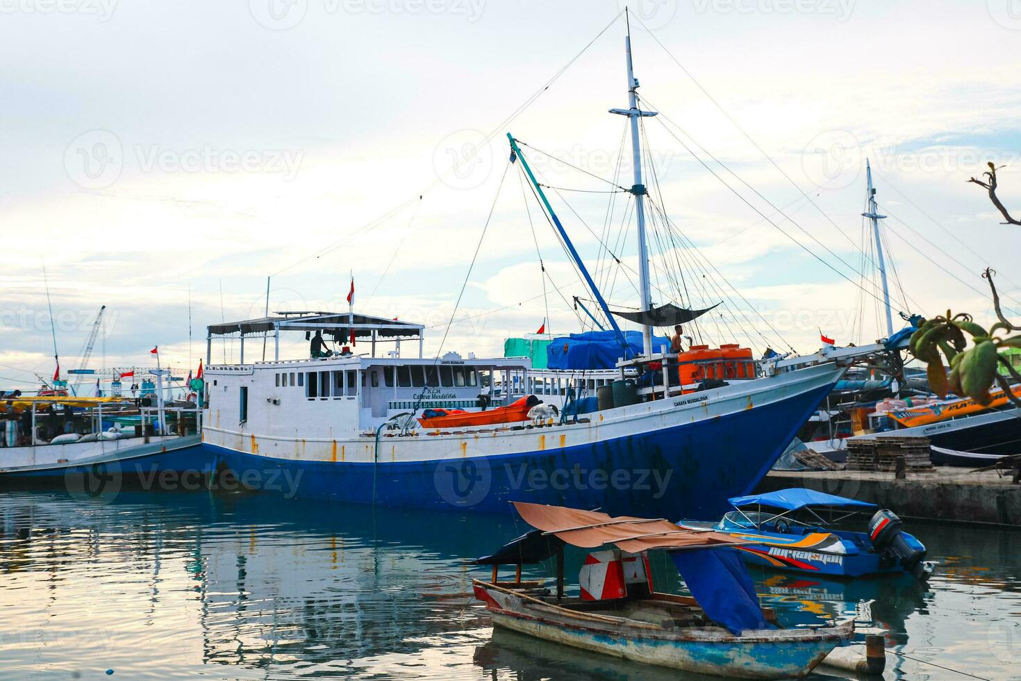 Several wooden boats and cargo ships moored at the traditional port while waiting for loading and unloading photo