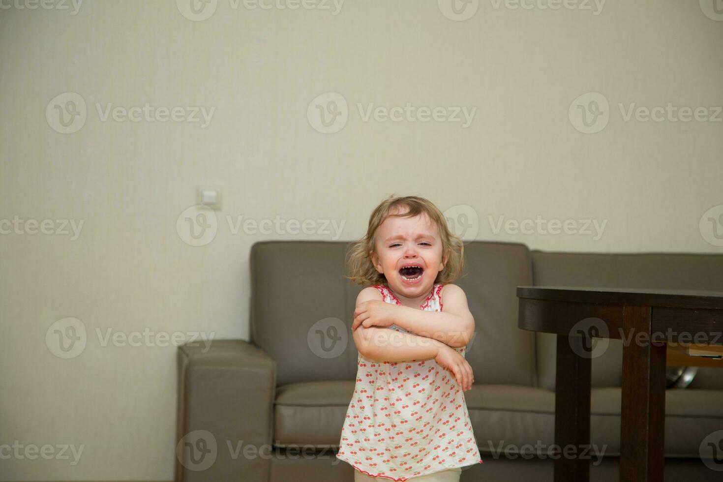 a little girl is crying in a room photo