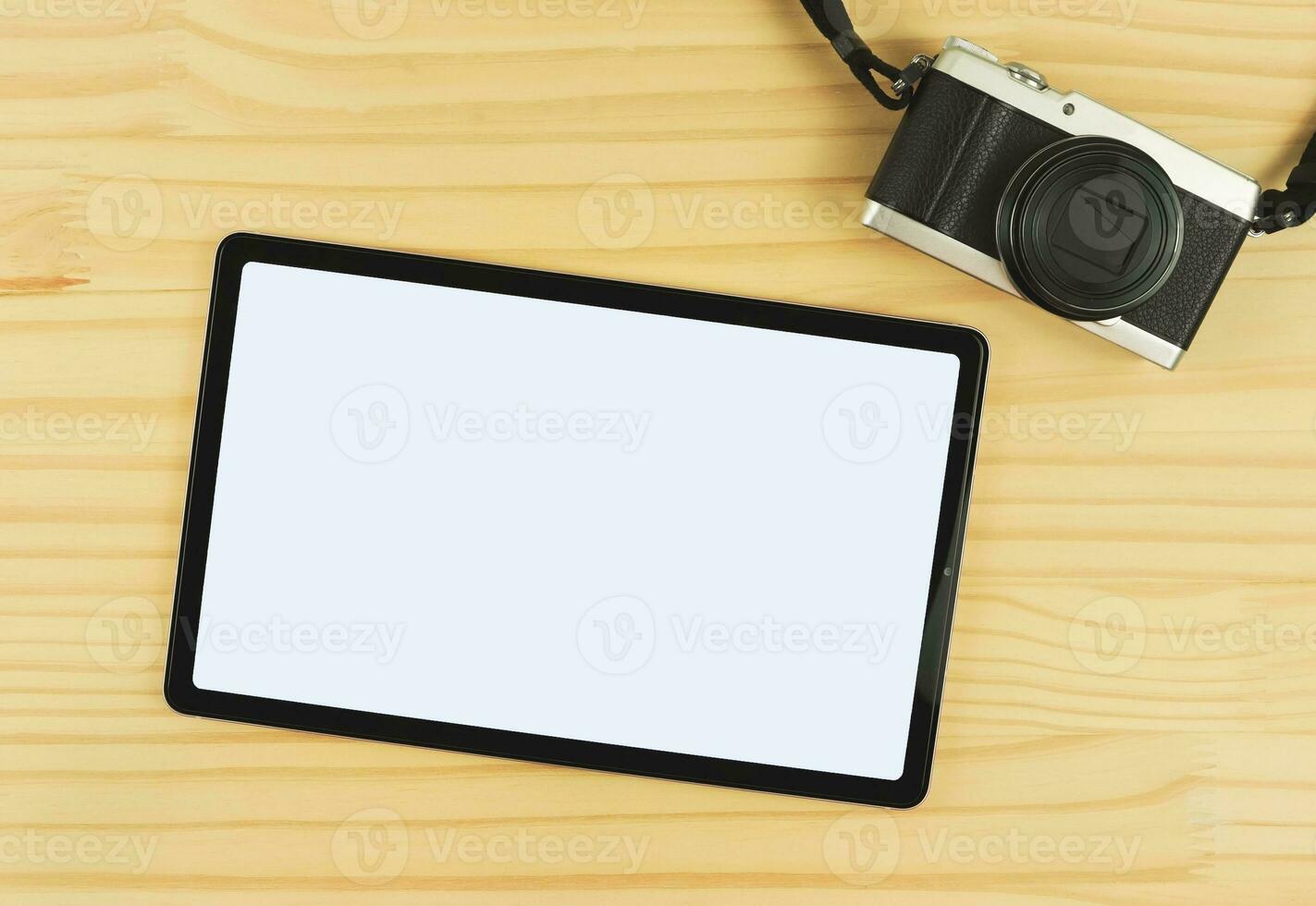 flat lay of digital tablet with blank white screen and digital camera isolated on wooden table background. photo