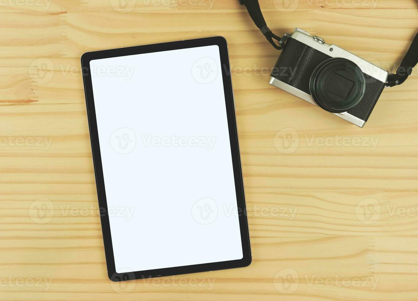 flat lay of digital tablet with blank white screen and digital camera isolated on wooden table background. photo