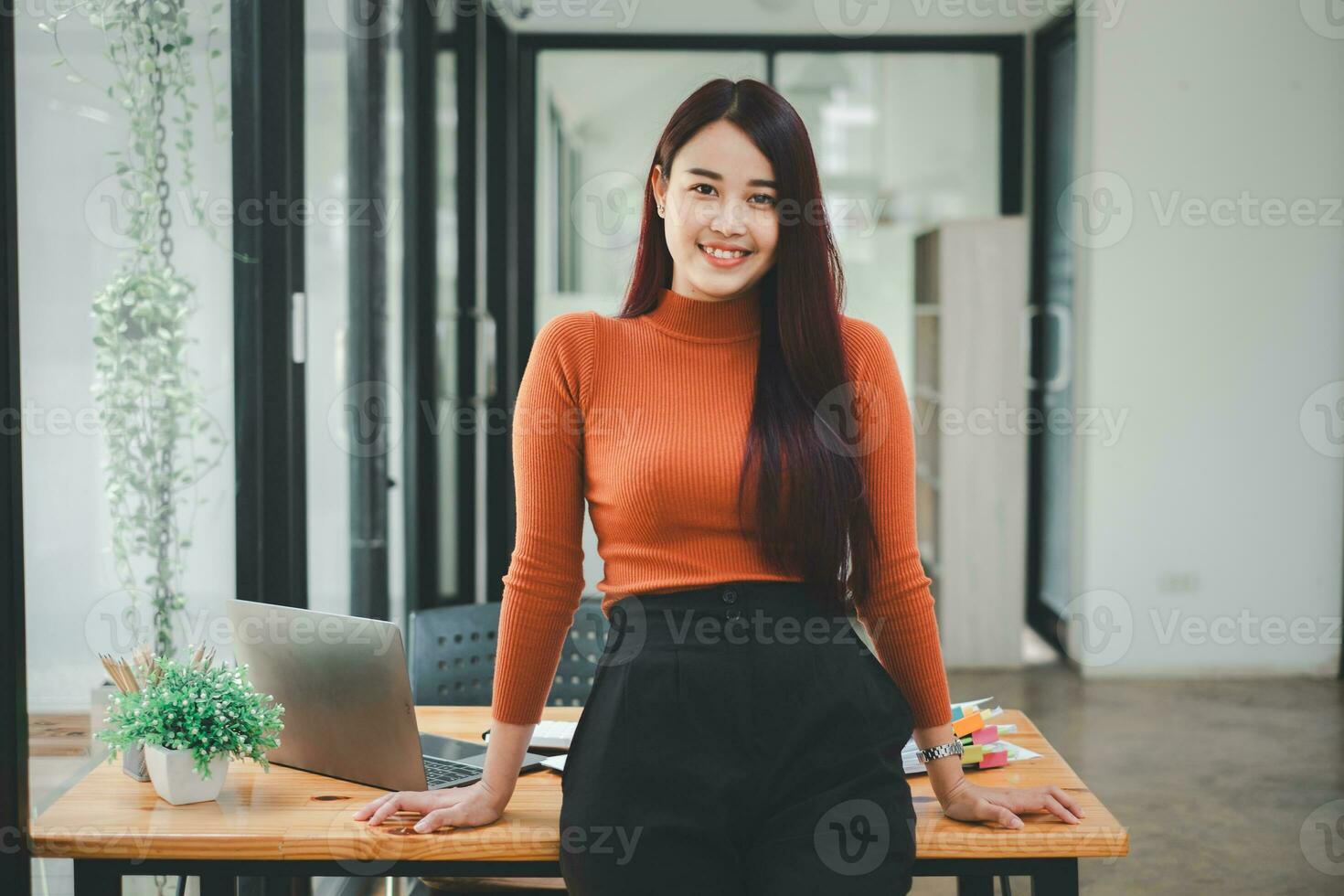 exitoso mujer de negocios en pie en creativo oficina y mirando a cámara. mujer empresario en un trabajo colaborativo espacio sonriente. foto