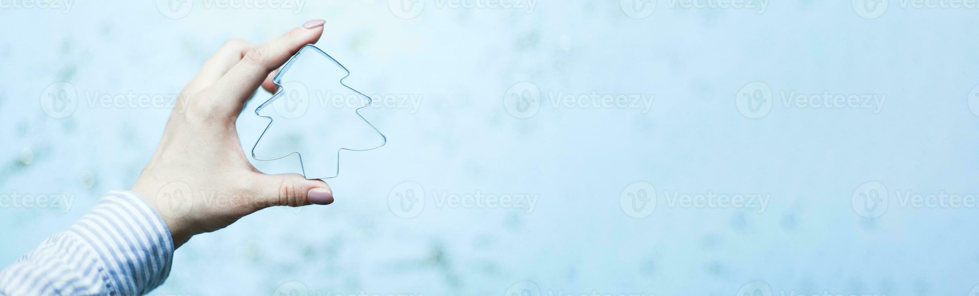 Banner A hand holds a Christmas tree shaped cookie cutter. Bake Christmas cookies photo