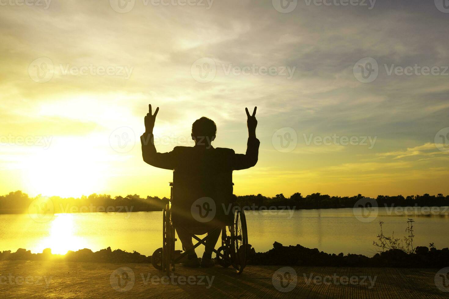 silueta joven discapacitado hombre viendo río fondo.él es aumento un mano a y sentado en silla de ruedas.desesperación,solitaria,esperanza.photo concepto depresión y paciente. foto