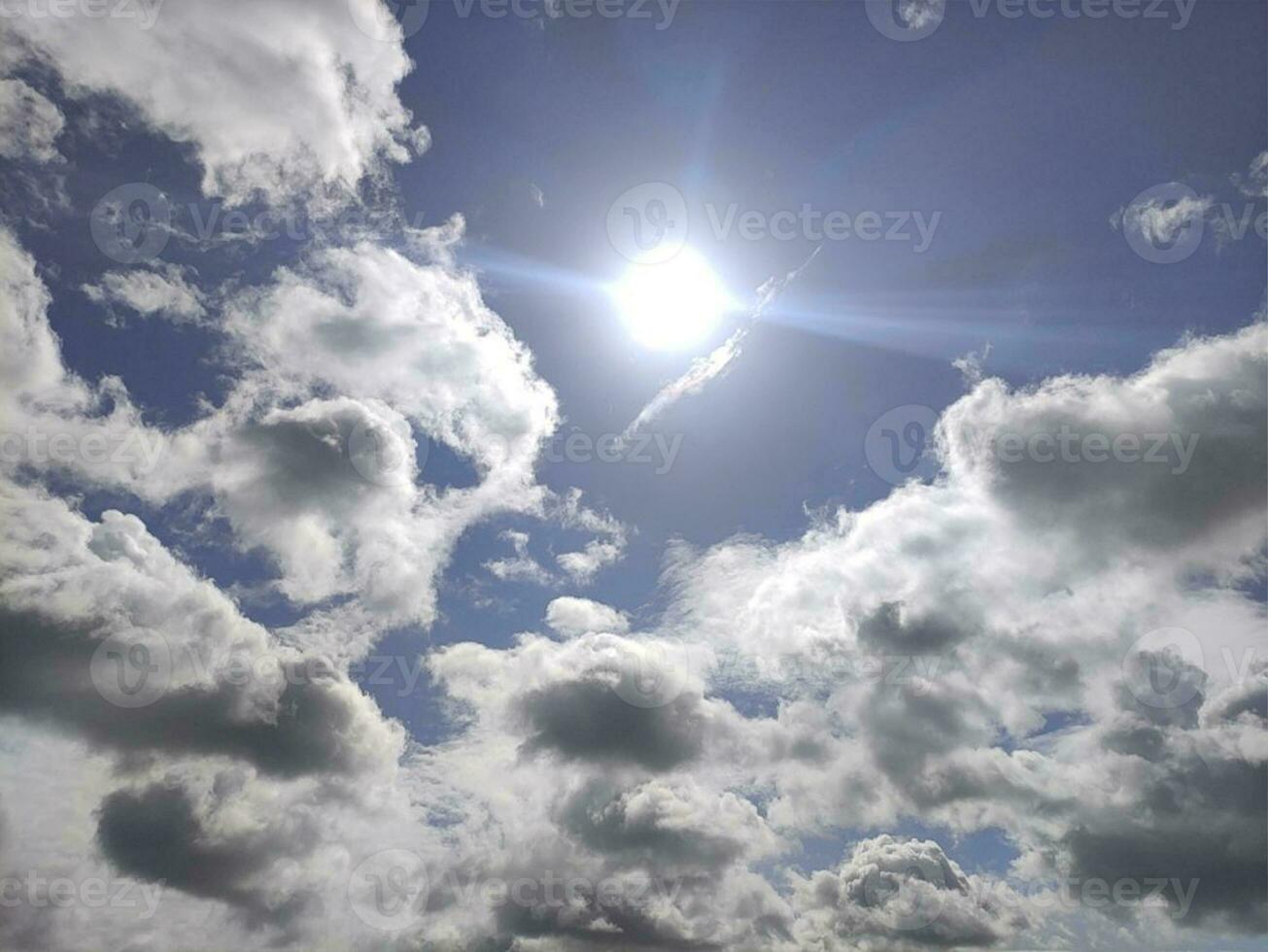 White clouds and sun over blue sky background. Fluffy cumulus clouds shapes photo