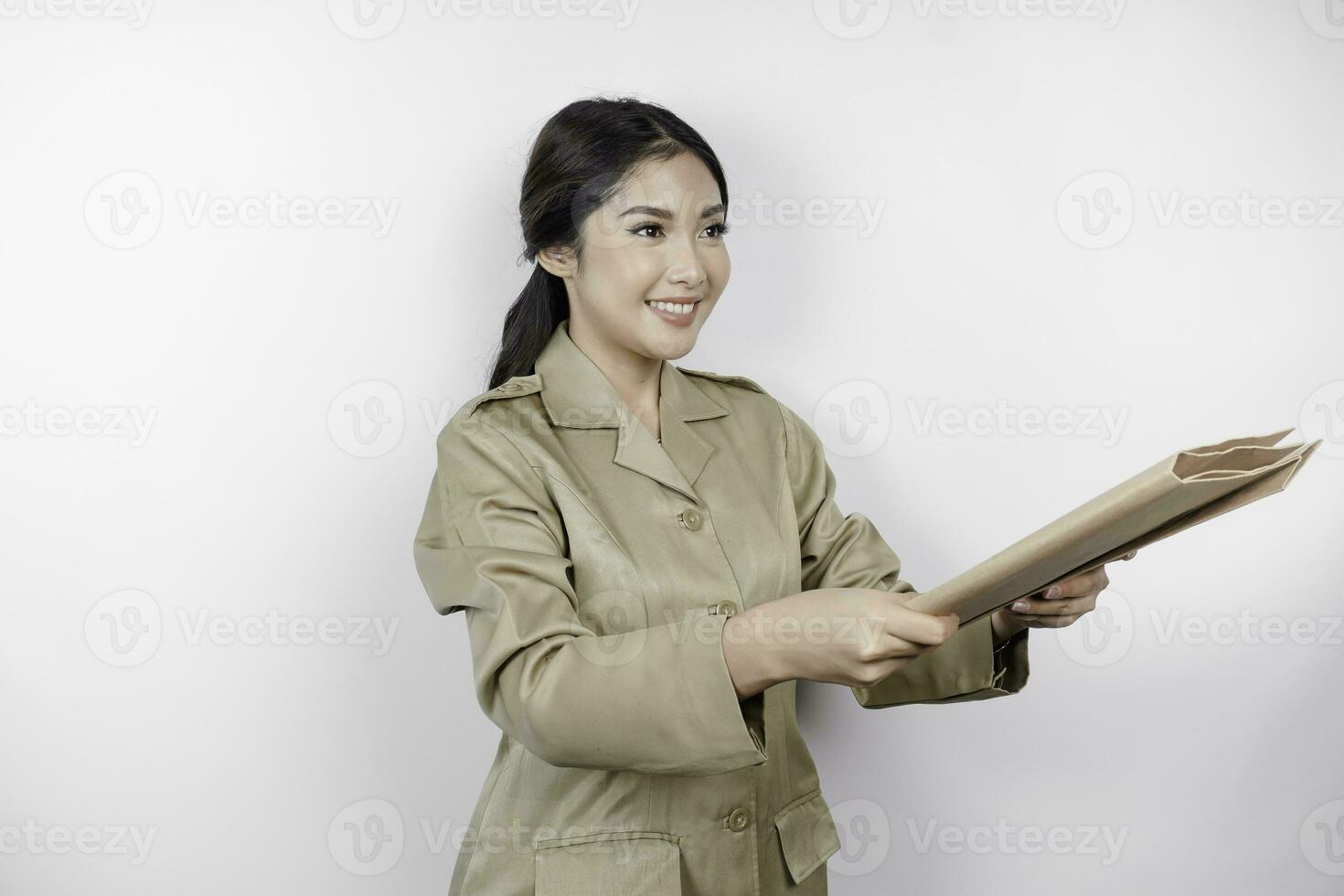 un joven hermosa asiático trabajador con marrón uniforme trayendo documento y entrega eso a el cámara. indonesio pps. foto