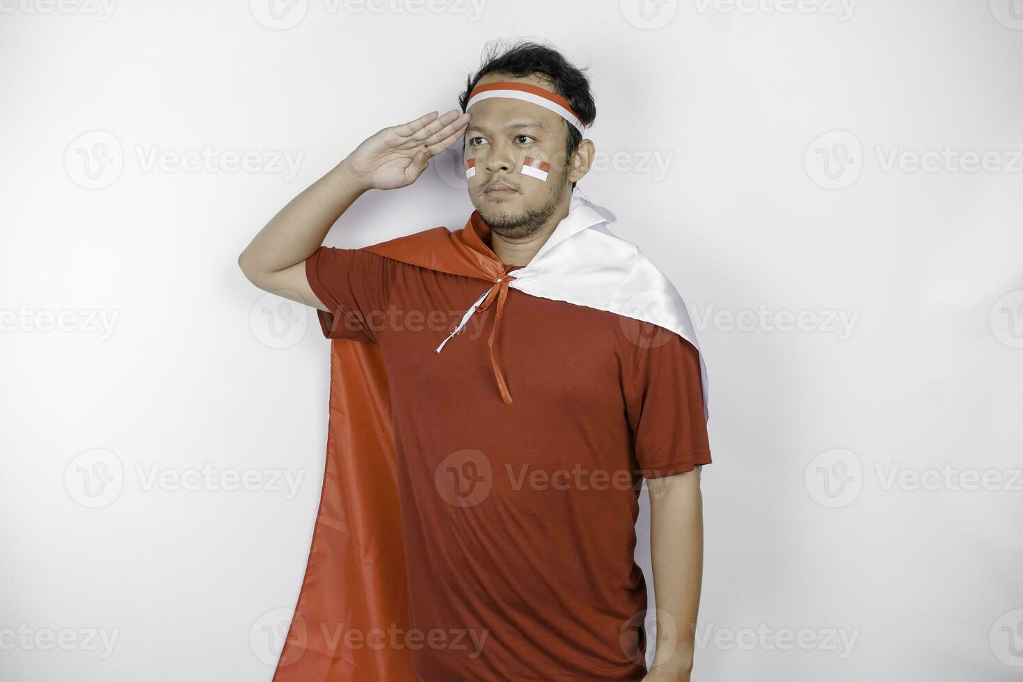 Indonesian man give salute with proud gesture while holding Indonesia's flag. Indonesia's independence day concept. photo