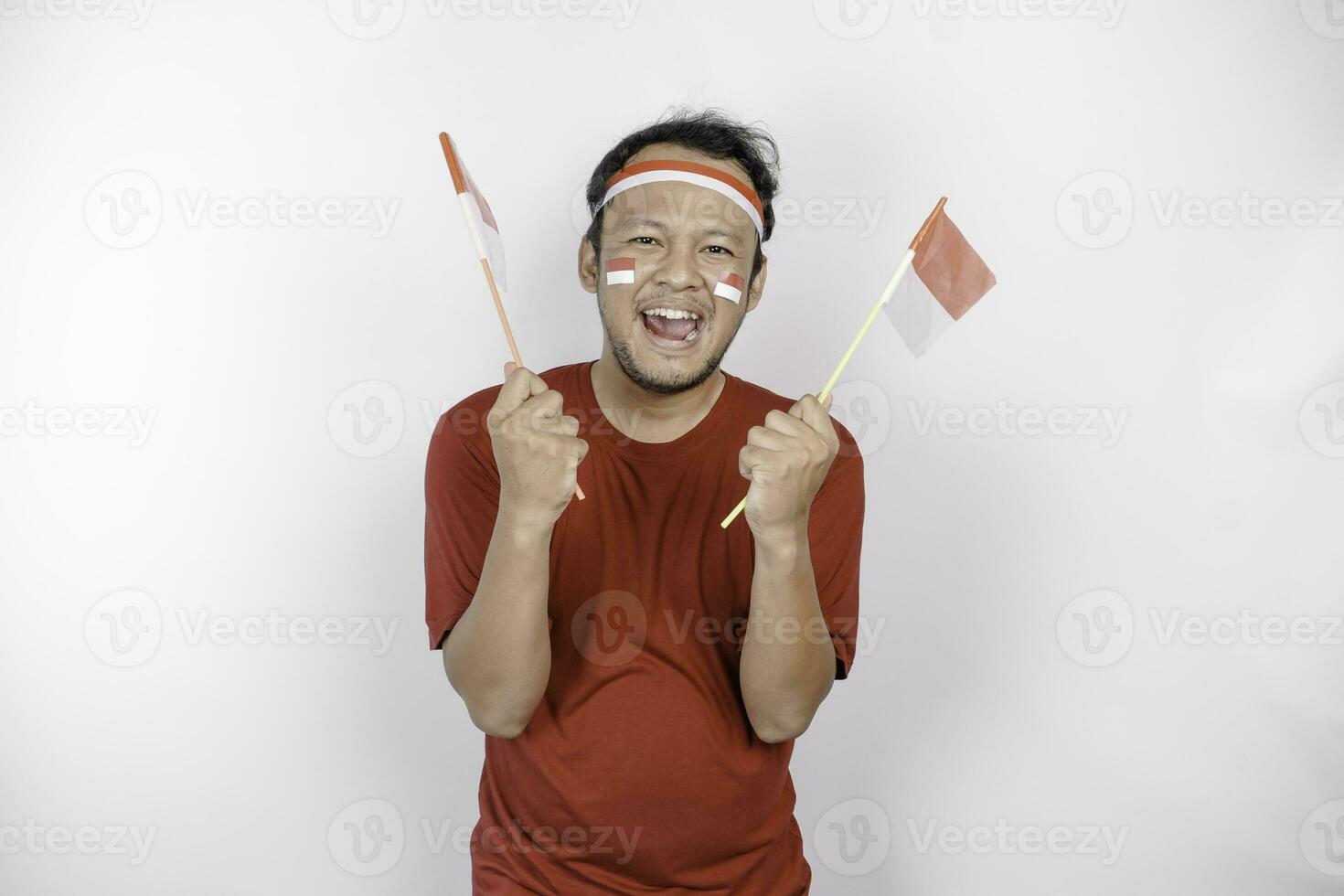 Happy smiling Indonesian man holding Indonesia's flag to celebrate Indonesia Independence Day isolated over white background. photo