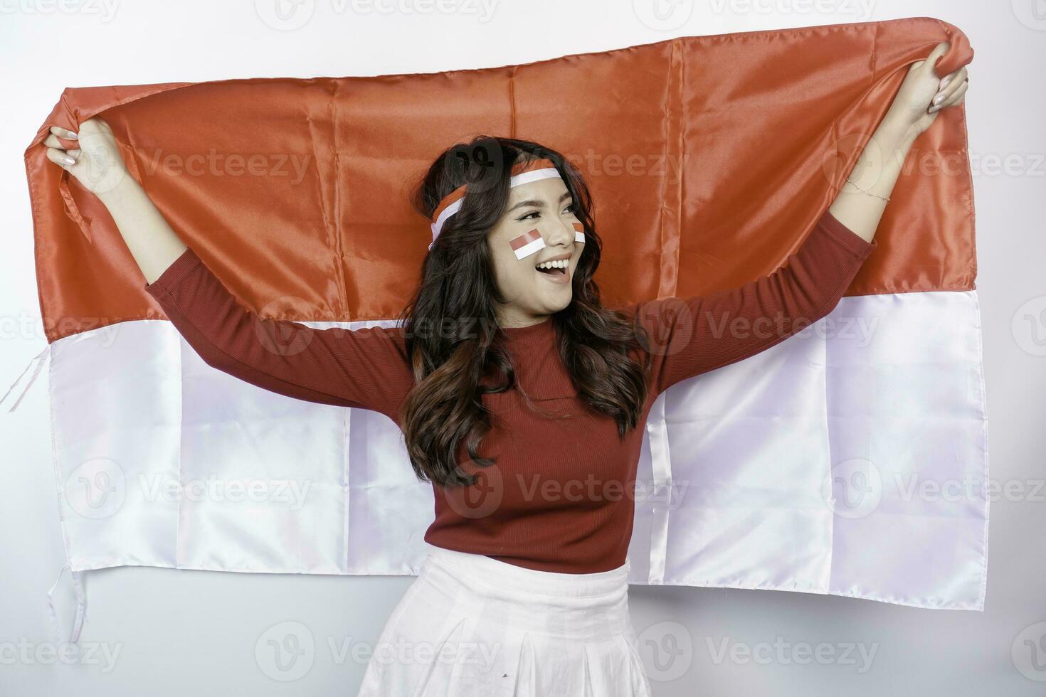 Happy smiling Indonesian woman holding Indonesia's flag to celebrate Indonesia Independence Day isolated over white background. photo