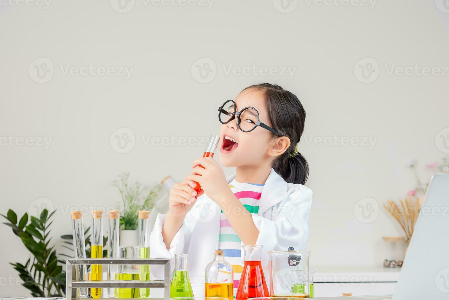 Asian little girl working with test tube science experiment in white classroom photo