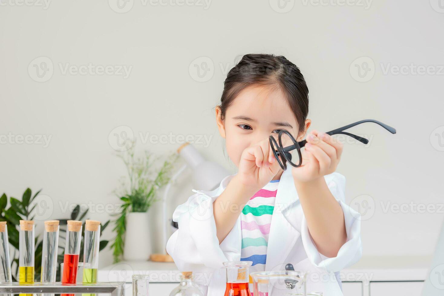 Asian little girl working with test tube science experiment in white classroom photo