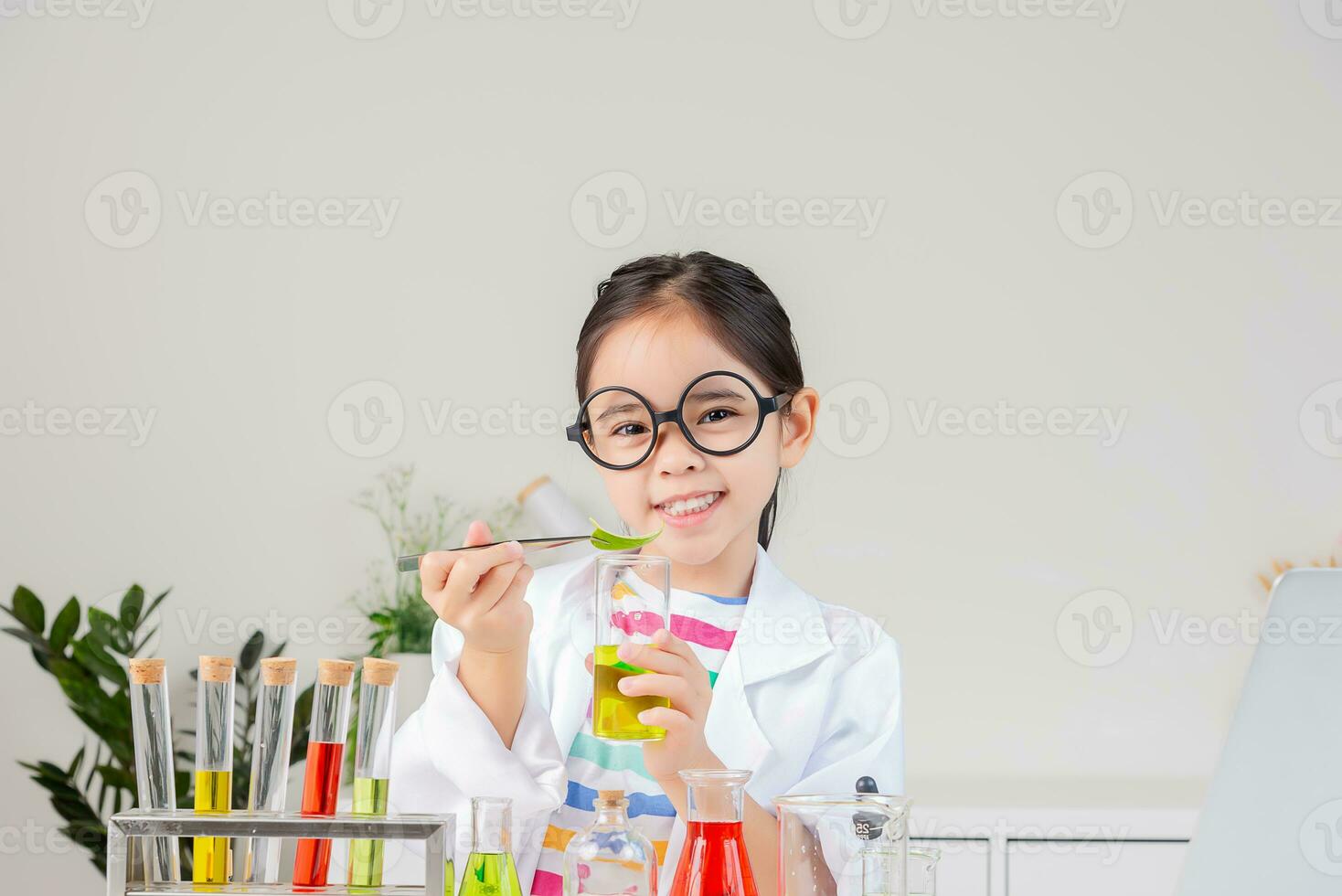 Asian little girl working with test tube science experiment in white classroom photo