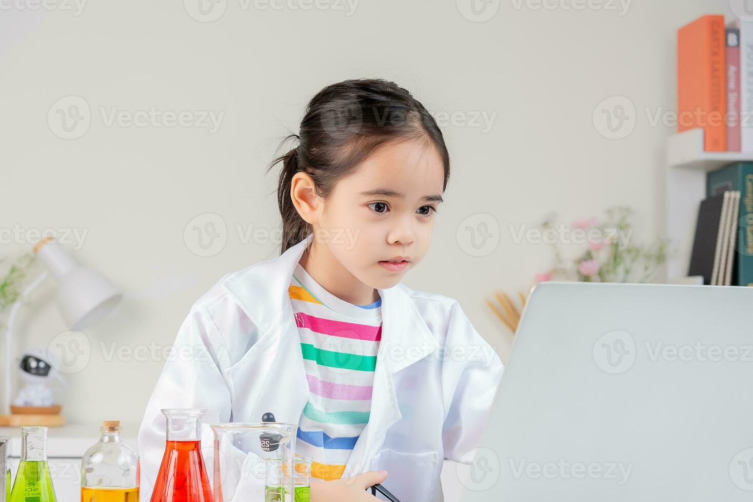 Asian little girl working with test tube science experiment in white classroom photo