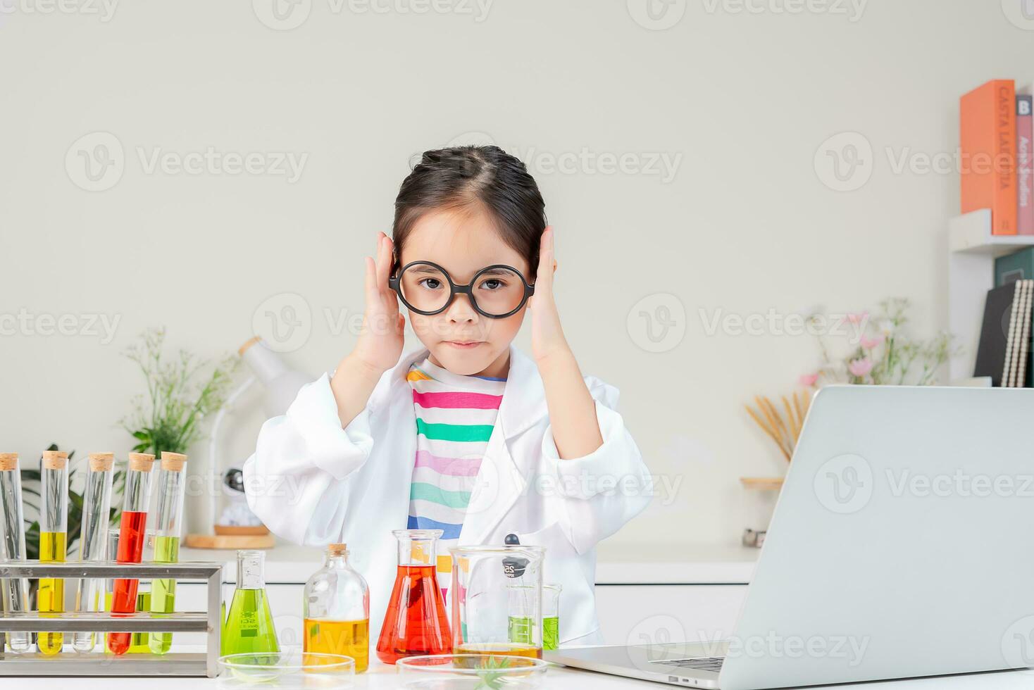 Asian little girl working with test tube science experiment in white classroom photo