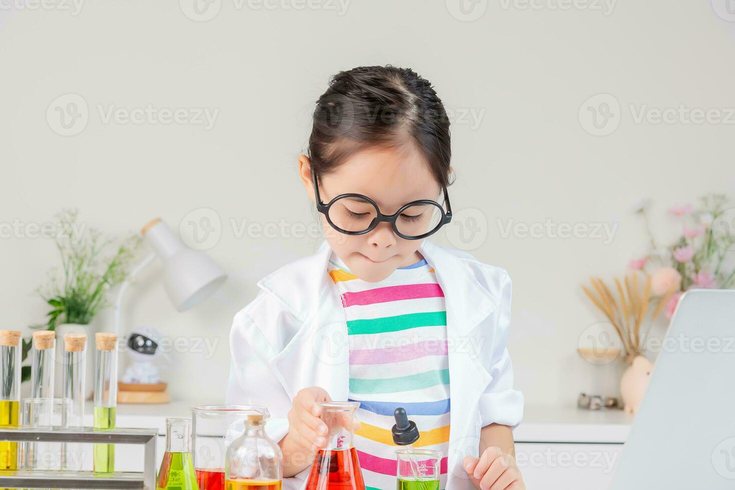 Asian little girl working with test tube science experiment in white classroom photo