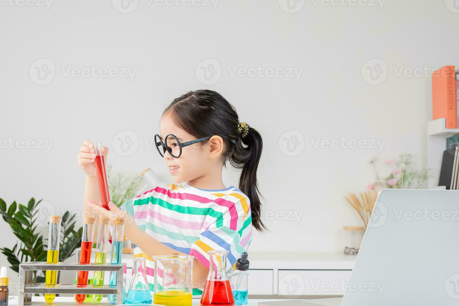 Asian little girl working with test tube science experiment in white classroom photo