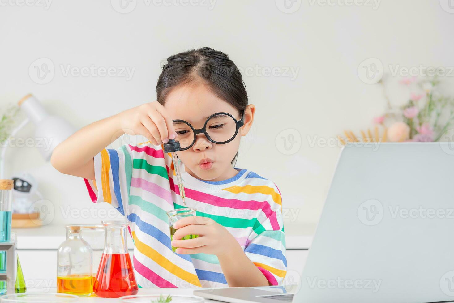 Asian little girl working with test tube science experiment in white classroom photo