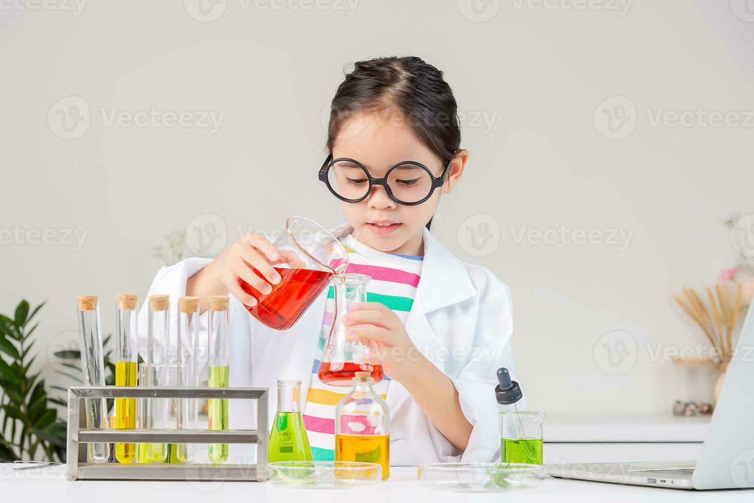 Asian little girl working with test tube science experiment in white classroom photo