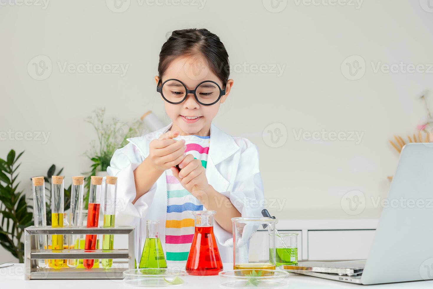 Asian little girl working with test tube science experiment in white classroom photo