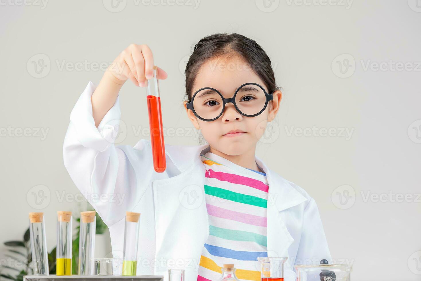 Asian little girl working with test tube science experiment in white classroom photo