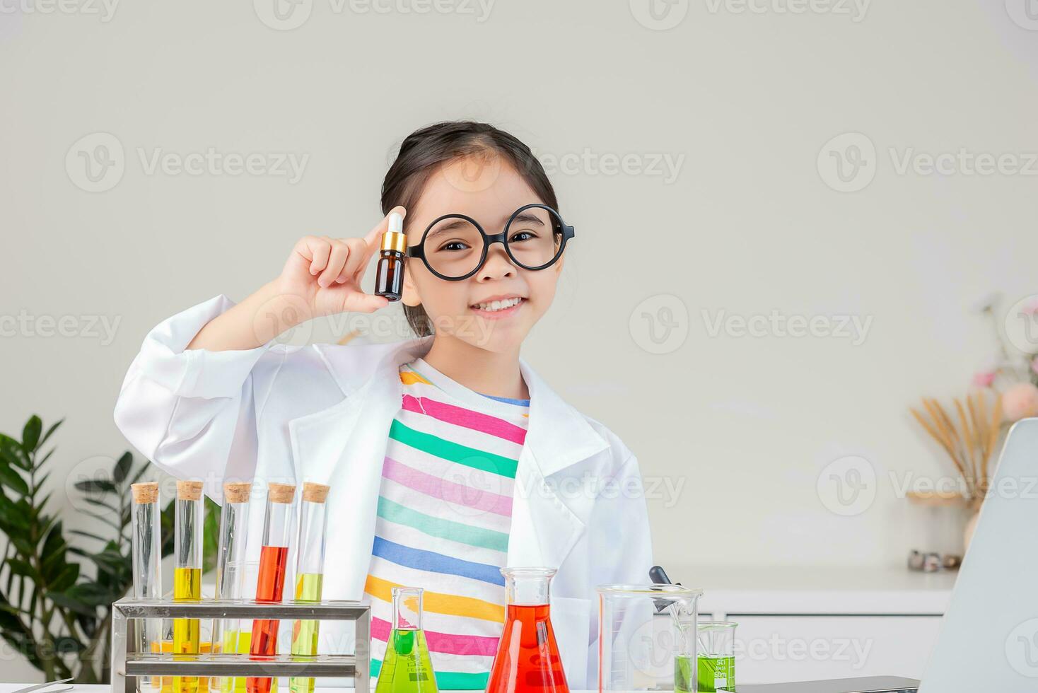 Asian little girl working with test tube science experiment in white classroom photo