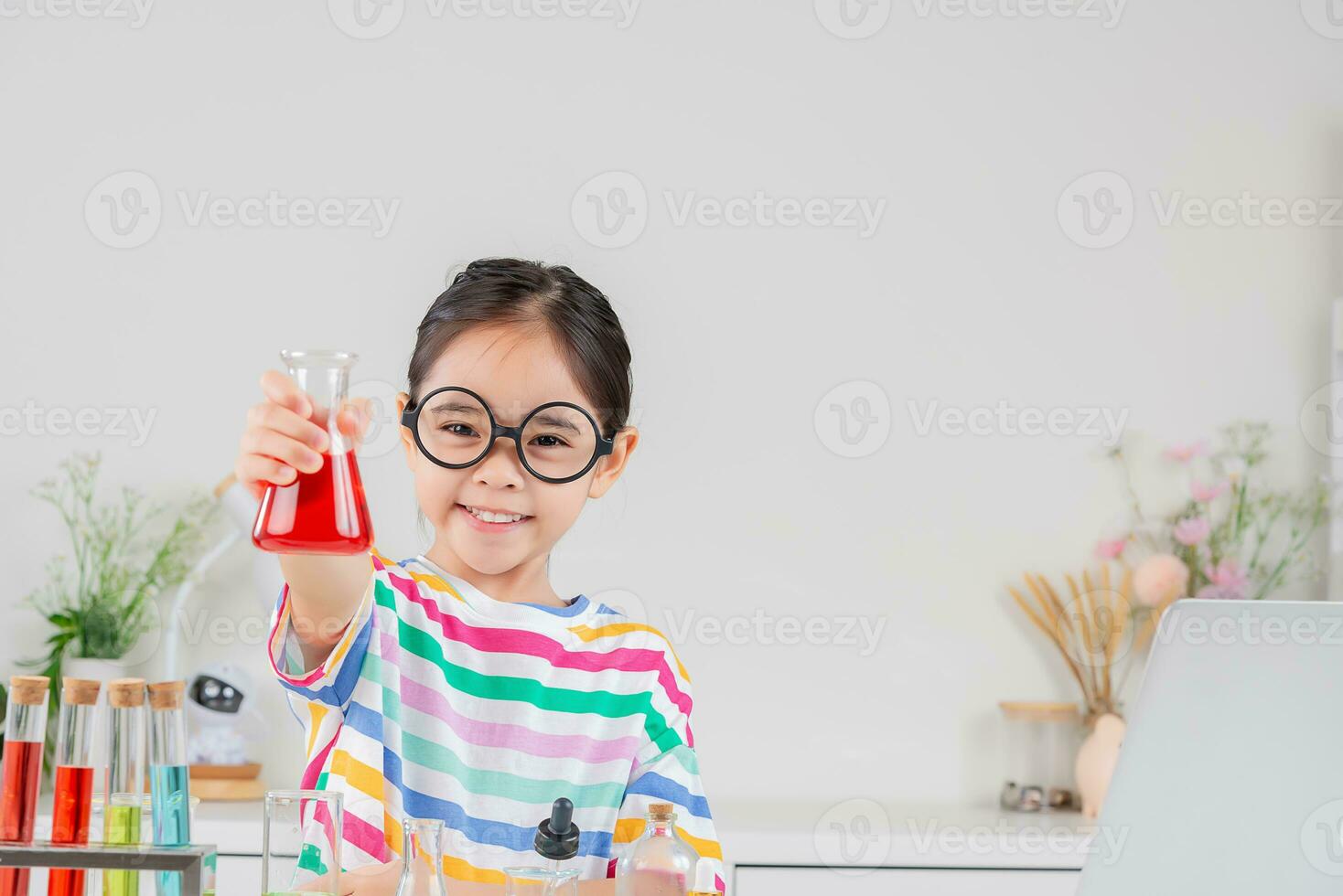 Asian little girl working with test tube science experiment in white classroom photo