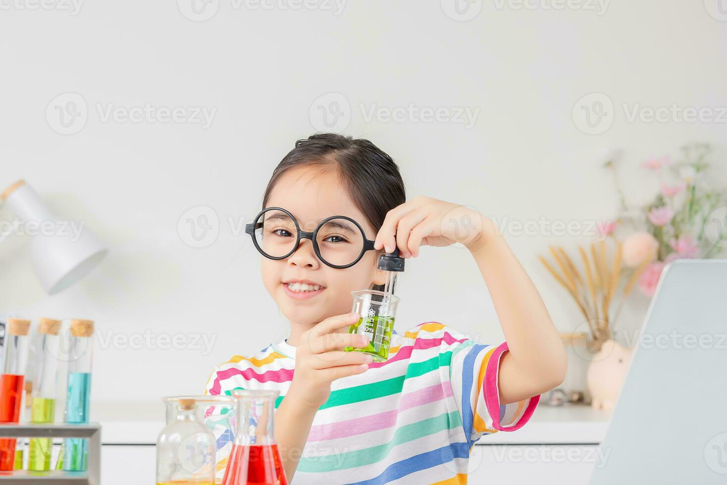 Asian little girl working with test tube science experiment in white classroom photo