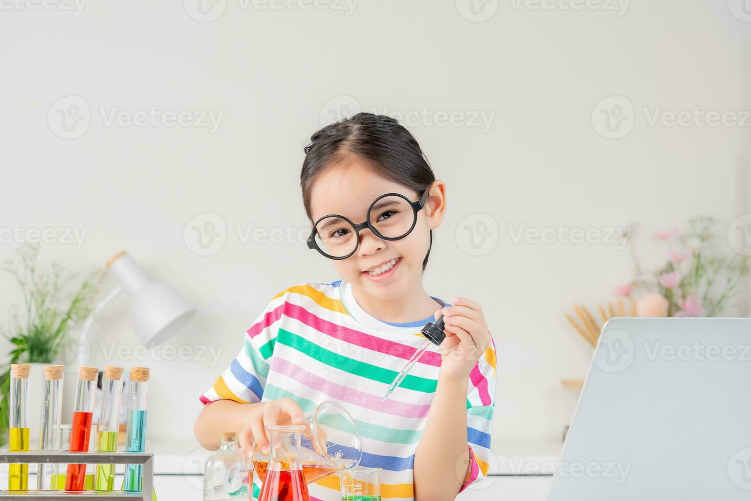 Asian little girl working with test tube science experiment in white classroom photo