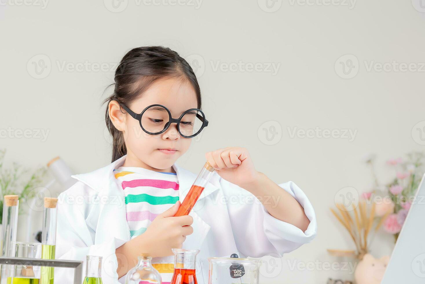 Asian little girl working with test tube science experiment in white classroom photo