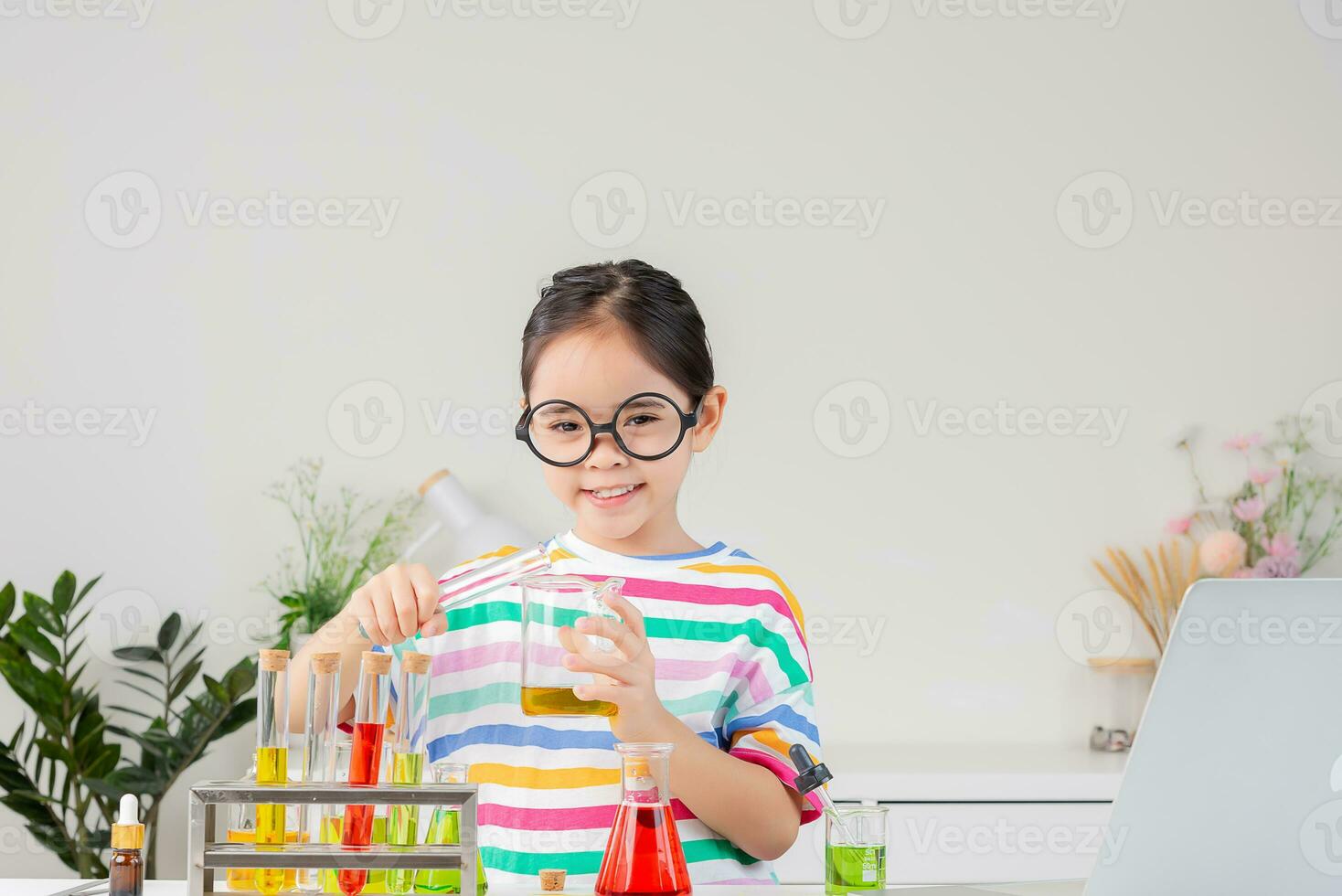 Asian little girl working with test tube science experiment in white classroom photo