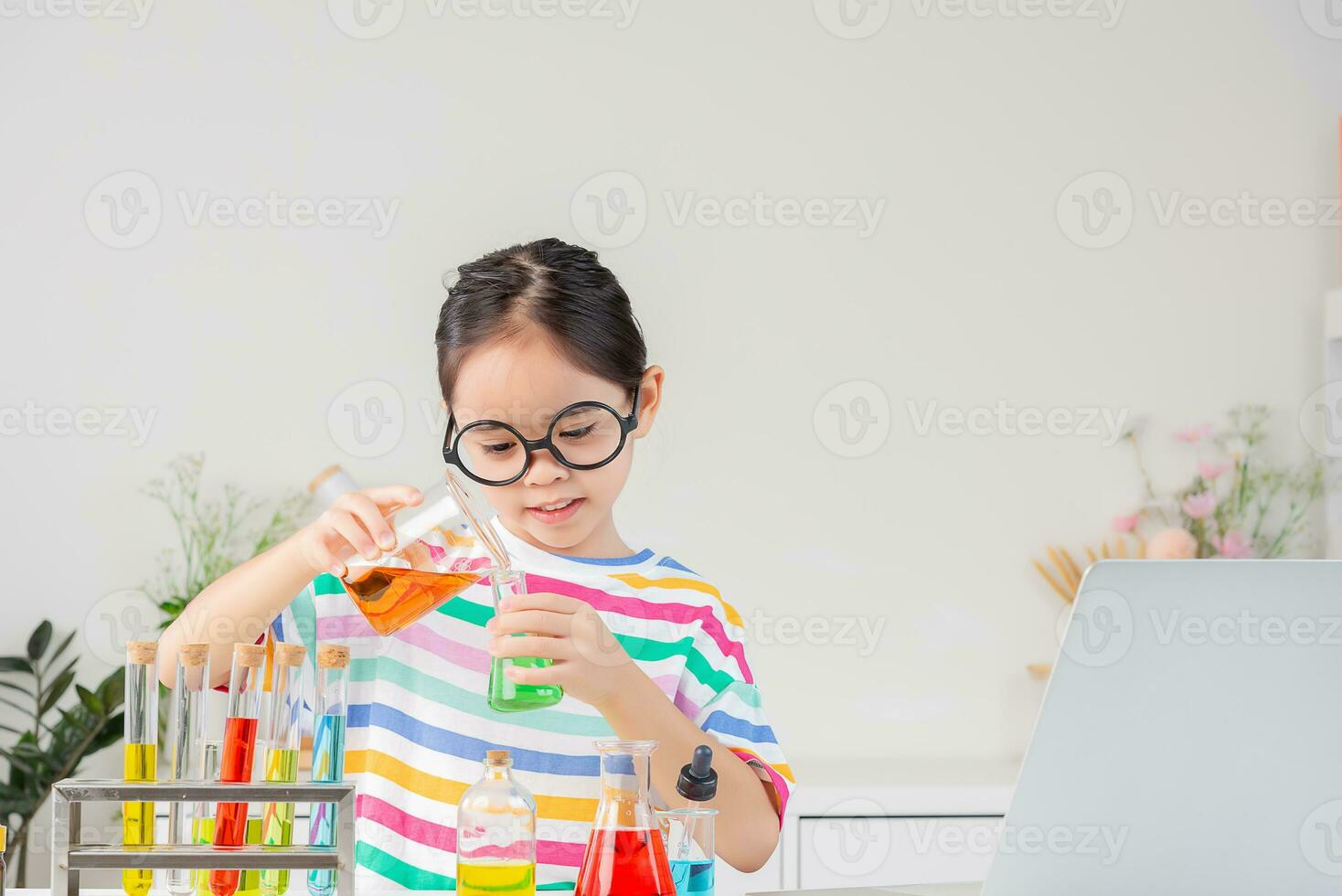 Asian little girl working with test tube science experiment in white classroom photo