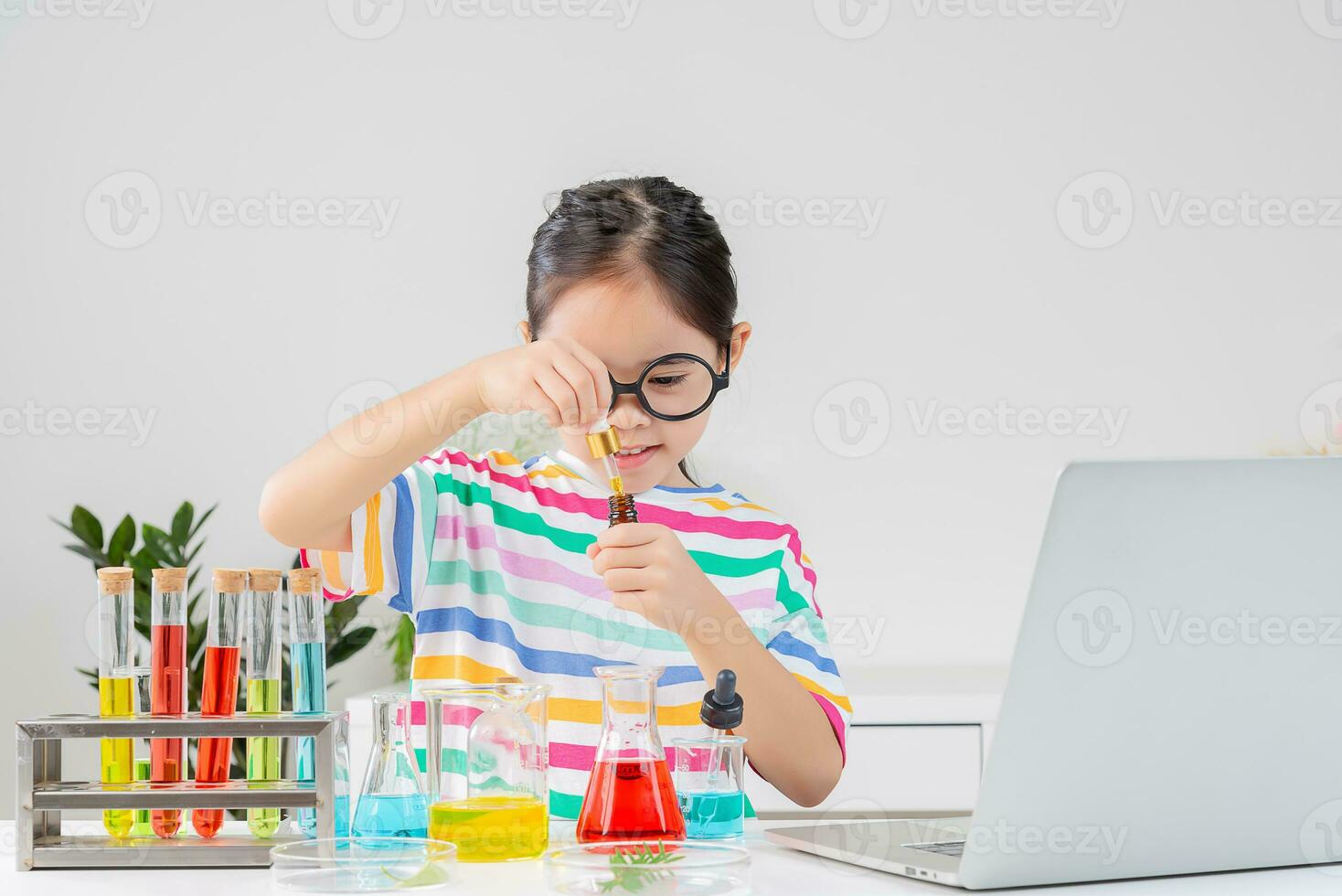 Asian little girl working with test tube science experiment in white classroom photo