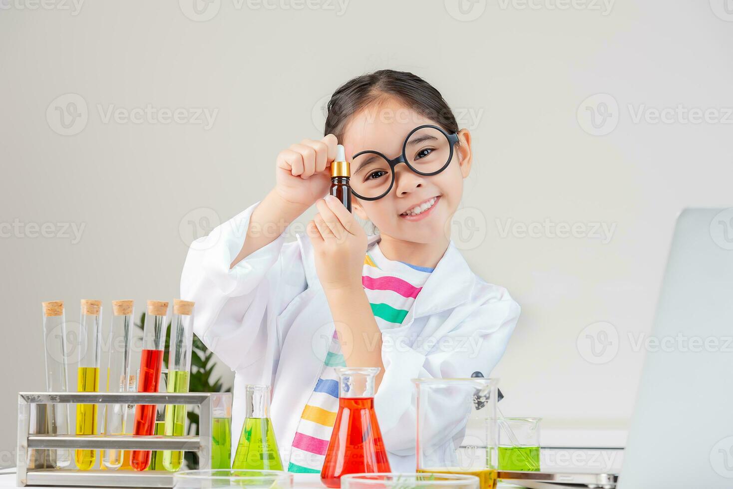 Asian little girl working with test tube science experiment in white classroom photo