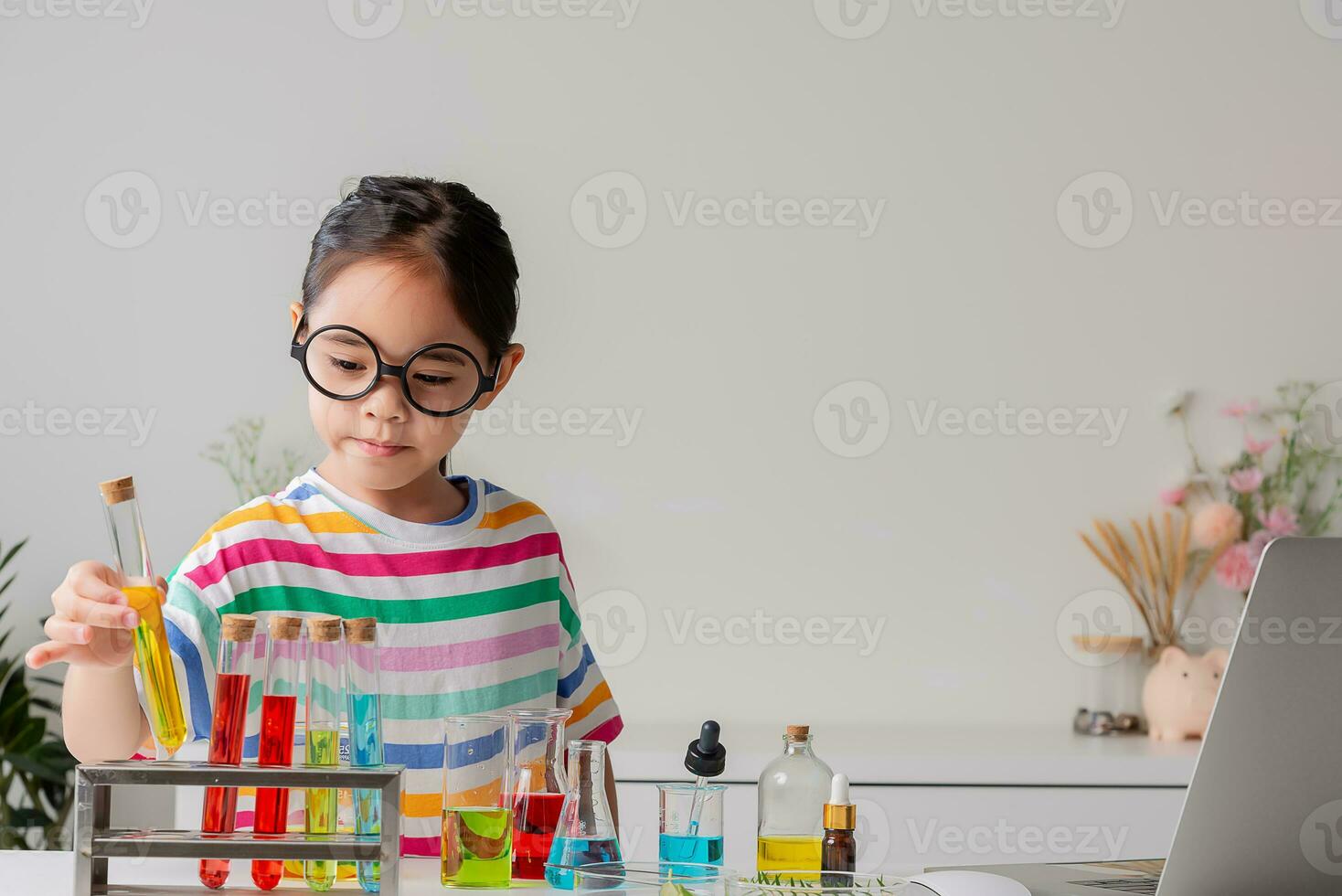Asian little girl working with test tube science experiment in white classroom photo