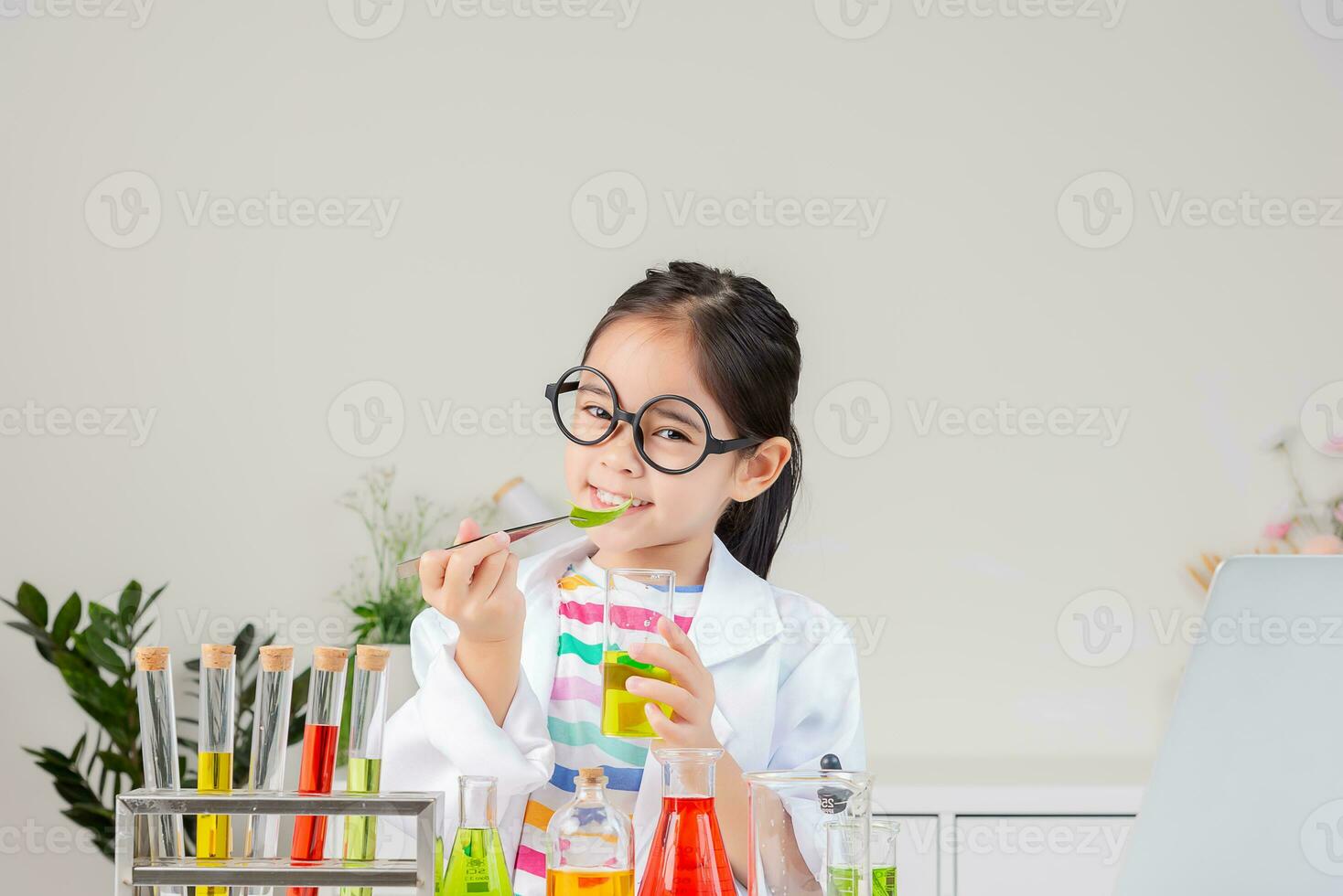 Asian little girl working with test tube science experiment in white classroom photo