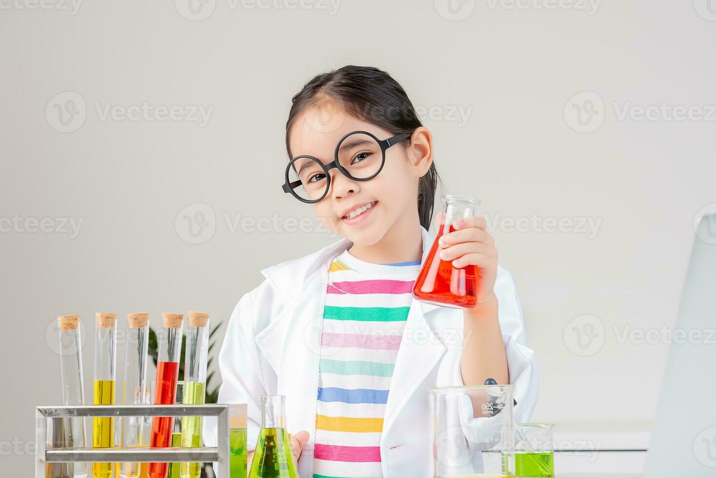 Asian little girl working with test tube science experiment in white classroom photo