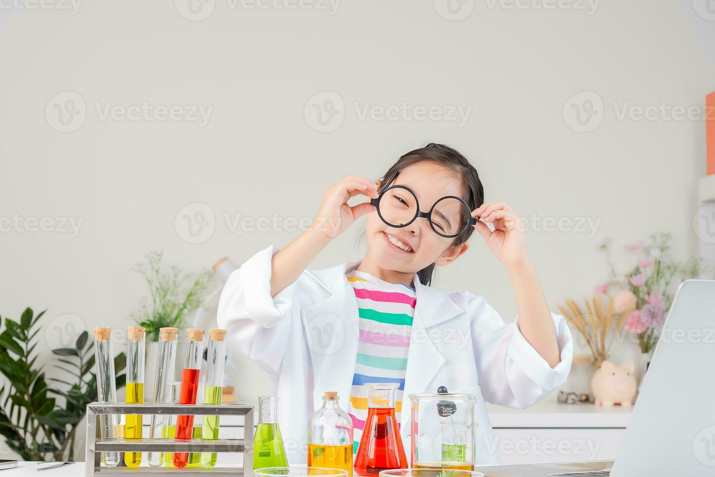 Asian little girl working with test tube science experiment in white classroom photo